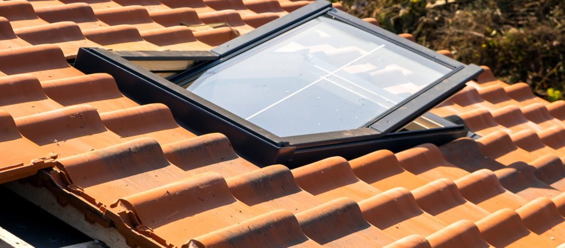 Overlapping rows of yellow ceramic roofing tiles mounted on wooden boards covering residential building roof under construction.