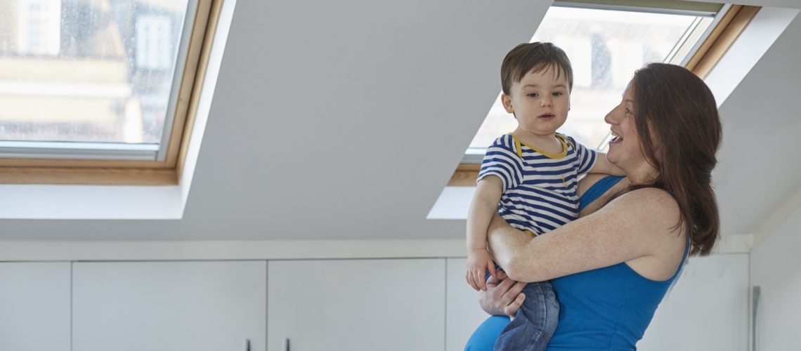 Side view of pregnant mother holding baby boy