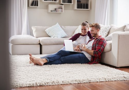 Young white couple sitting on the floor at home using laptop